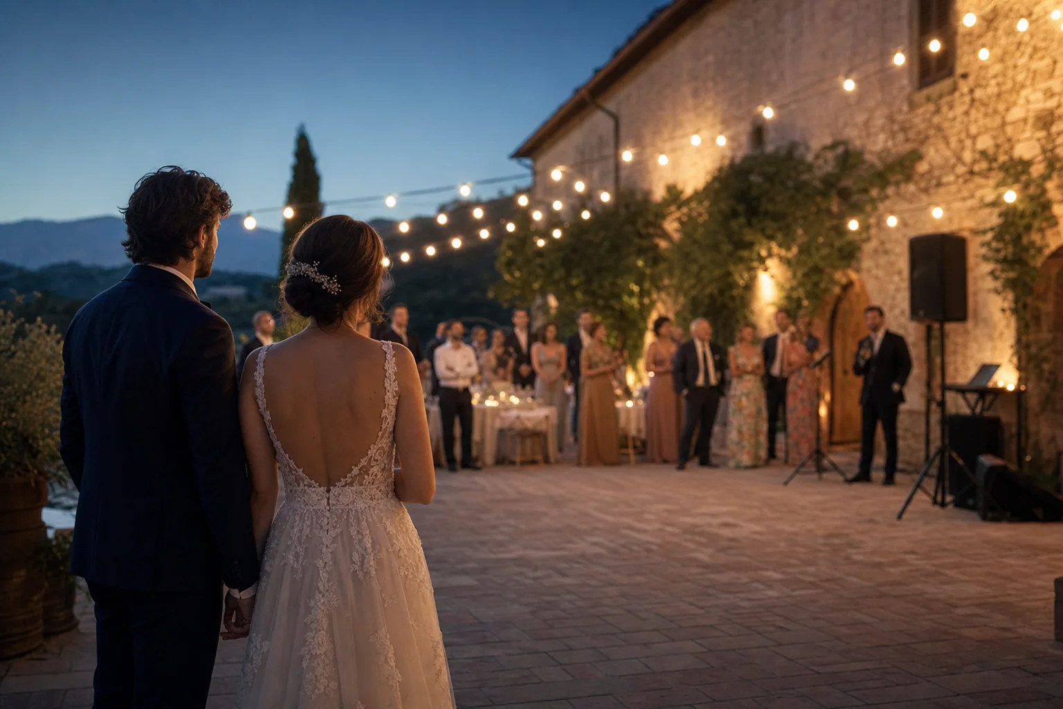 Due sposi osservano gli invitati durante un ricevimento serale